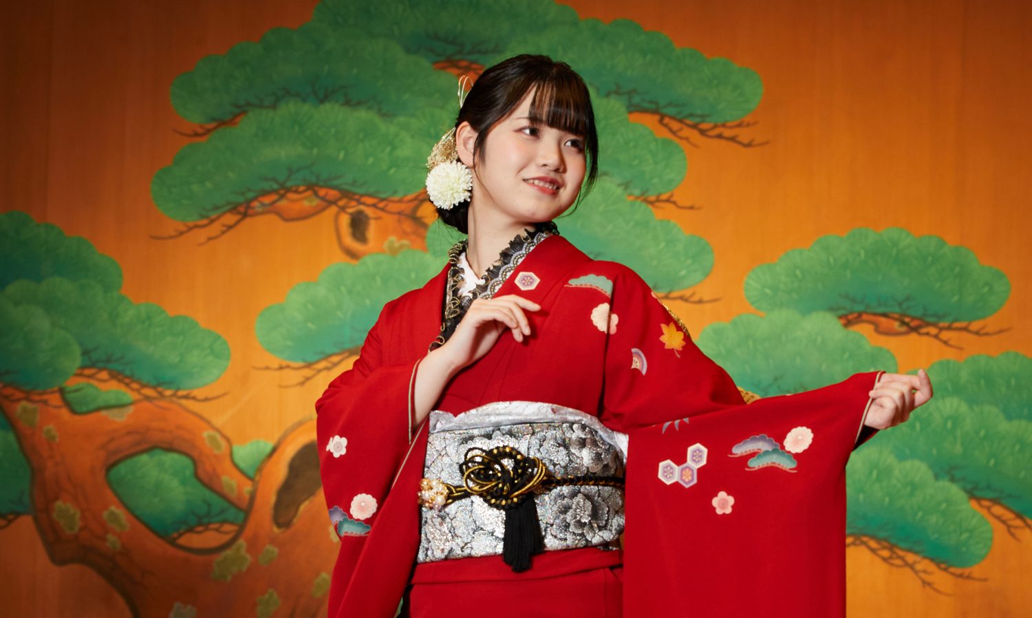 伝統的な松の屏風を背景にした振袖姿の新成人